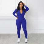 A woman wearing a black Arenzza solid color half zip seamless jumpsuit, showcasing its fitted design and high collar.
