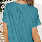 A woman wearing a light blue women's casual pleated V-neck short-sleeve top by Arenzza, styled casually.
