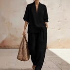 A woman wearing a women's casual V-neck top and wide-leg pants set by Arenzza, featuring a relaxed fit and stylish design.