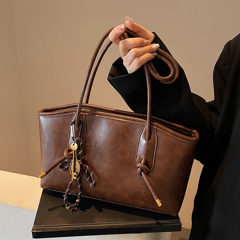 A women's vintage PU leather shoulder bag with a classic design, featuring a top handle and shoulder strap, in brown tones.