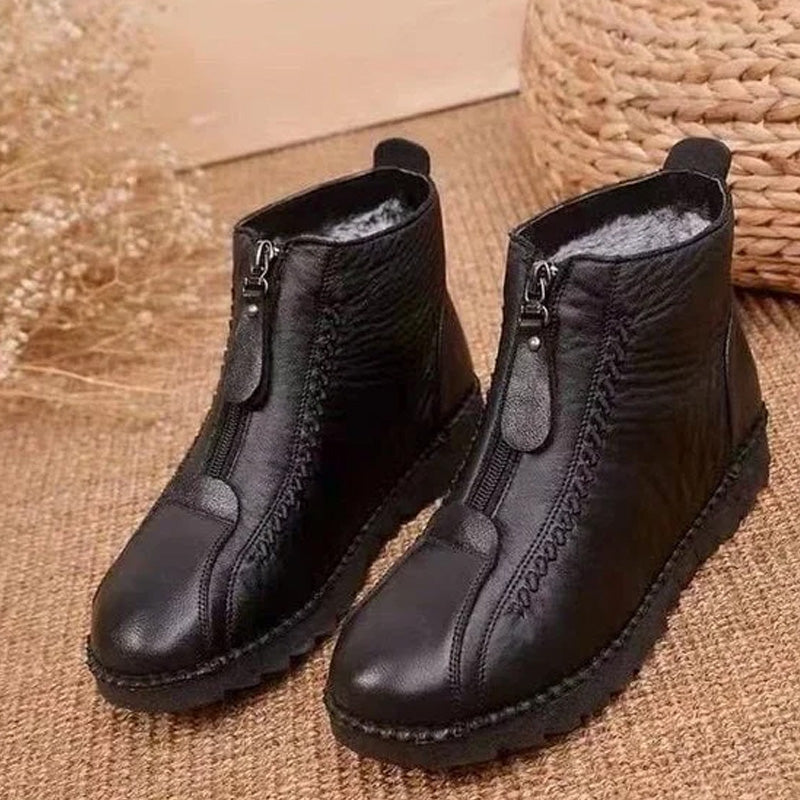 A pair of Arenzza women's winter ankle boots with side zippers, thermal insulation, water-resistant material, shown on a model.