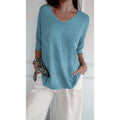 A beige solid color knitted V-neck top from Arenzza, displayed on a hanger, showcasing its soft fabric and classic style.