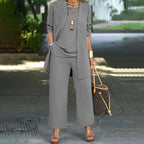 A woman wearing a minimalist three-piece set from Arenzza, featuring wide-leg pants, a cardigan, and a top in luxe stretch fabric.