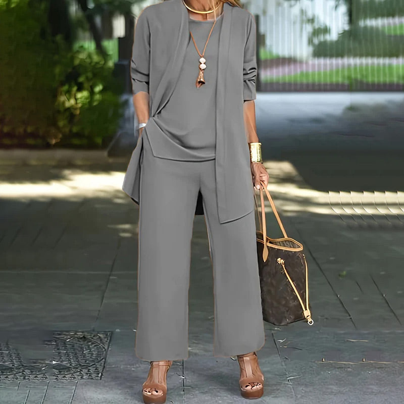 A woman wearing a minimalist three-piece set from Arenzza, featuring wide-leg pants, a cardigan, and a top in luxe stretch fabric.