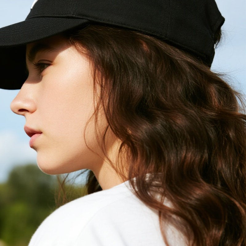 A brown 2-in-1 curly hair baseball cap wig from Arenzza, showing the cap's front view with curly hair extending from the brim.