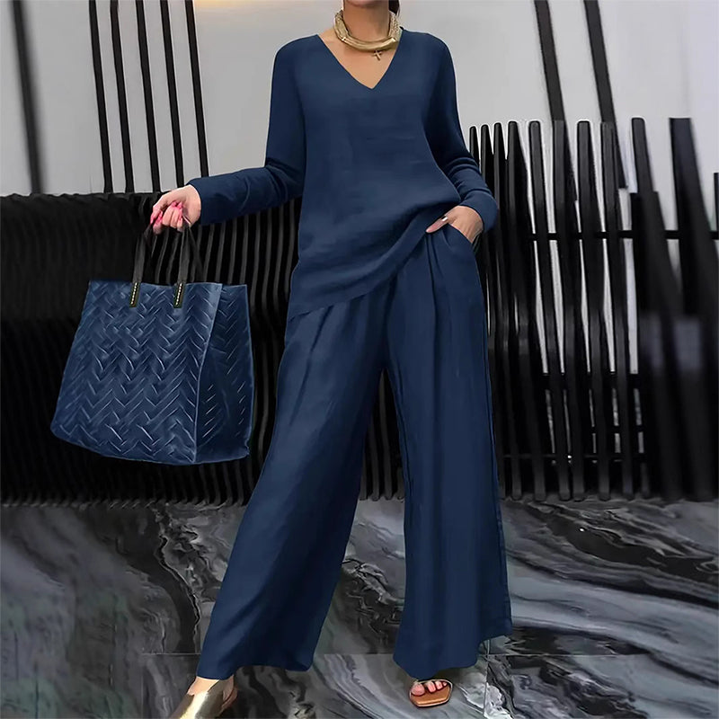 A woman wearing a women's V-neck lounge set with wide-leg pants by Arenzza, displayed in a cozy indoor setting.