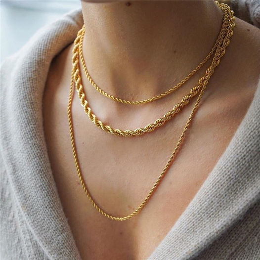 A layered gold twist rope necklace and bracelet set from Arenzza, featuring elegant, intertwined jewelry on a neutral background.