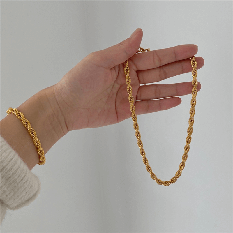 Layered gold twist rope necklaces and bracelets from Arenzza, featuring elegant, intertwined jewelry pieces for stylish accessorizing.