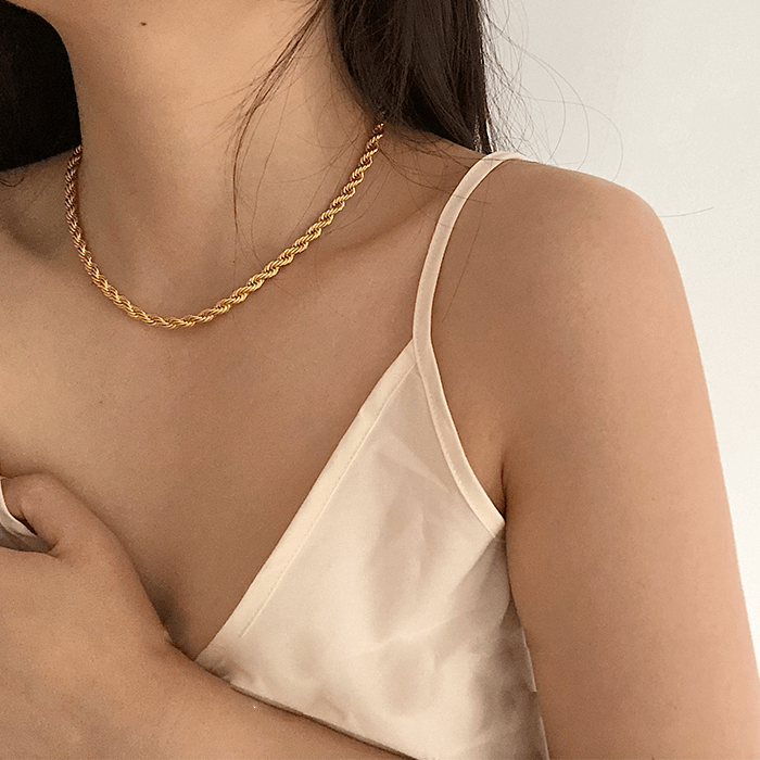 Layered gold twist rope necklaces and bracelets from Arenzza, featuring elegant, intertwined jewelry on a neutral background.