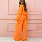 A woman wearing a minimalist round neck top and wide-leg pants 2-piece set by Arenzza, shown in a casual, stylish outfit.