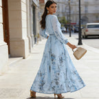 A woman wearing an elegant V-neck floral pleated maxi dress by Arenzza, featuring a flowing skirt and vibrant floral pattern.