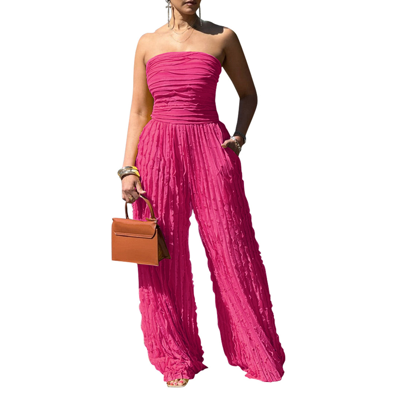 A woman wearing a strapless crinkle wide-leg jumpsuit by Arenzza, showcasing its relaxed fit and stylish design.