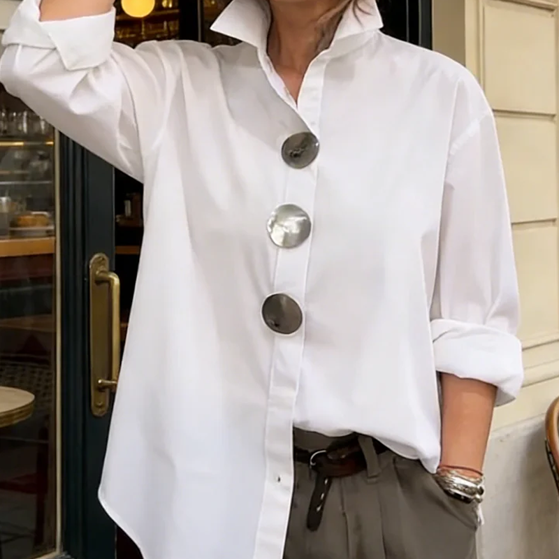 A woman wearing an oversized Arenzza women's button-down shirt with bold statement buttons, showcasing relaxed fit and stylish details.