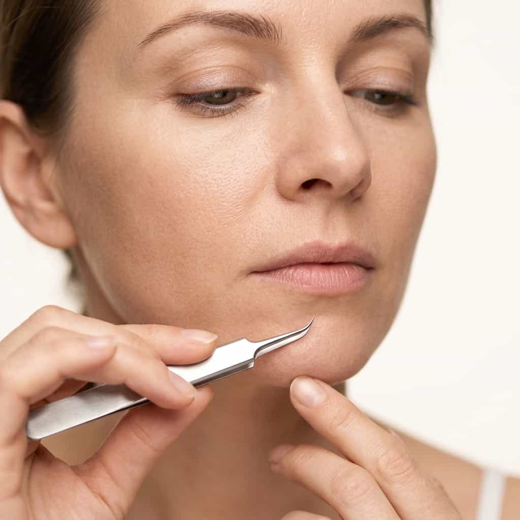 A woman using a stainless steel blackhead remover tool from Arenzza in a skincare routine, focusing on pore care and hygiene.