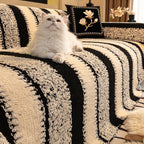 A soft plush non-slip couch cover by Arenzza, in a cozy light beige color, draped over a sofa in a living room setting.