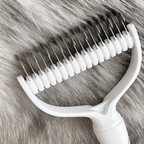 Arenzza dual-sided pet grooming rake with stainless steel teeth for removing loose fur from dogs and cats.