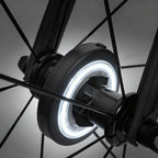 Arenzza LED cycling wheel hub light attached to a bicycle wheel, glowing with vibrant colors for night riding safety and visibility.