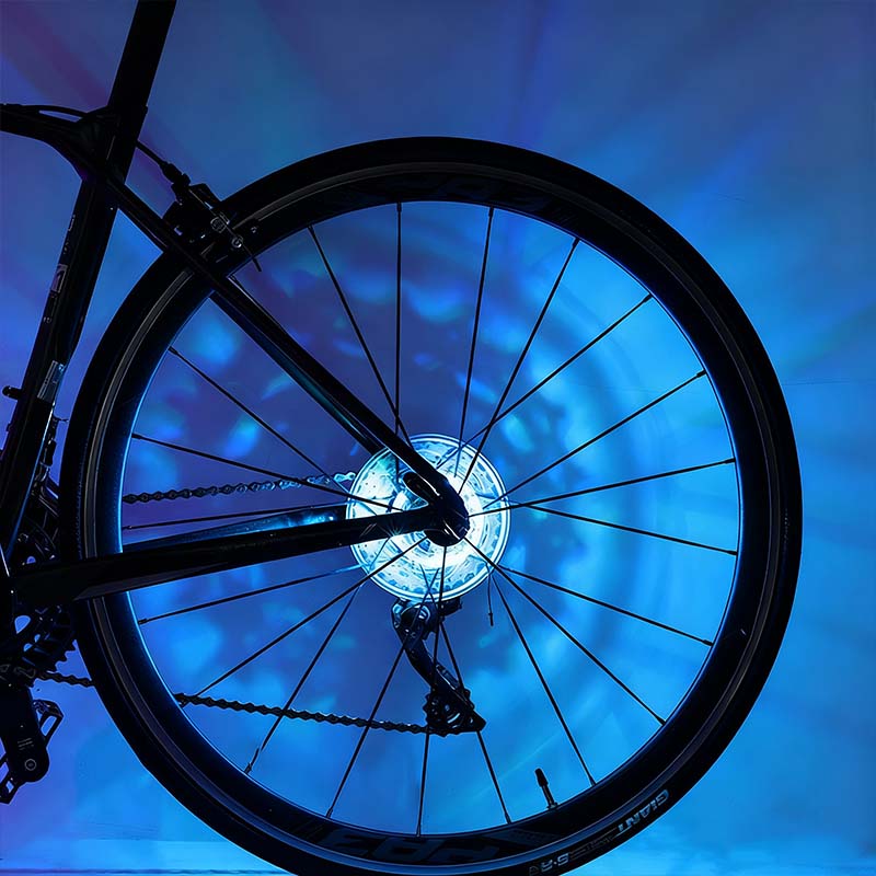 Arenzza LED cycling wheel hub light installed on a bike wheel for night riding, showcasing vibrant illumination and outdoor setting.