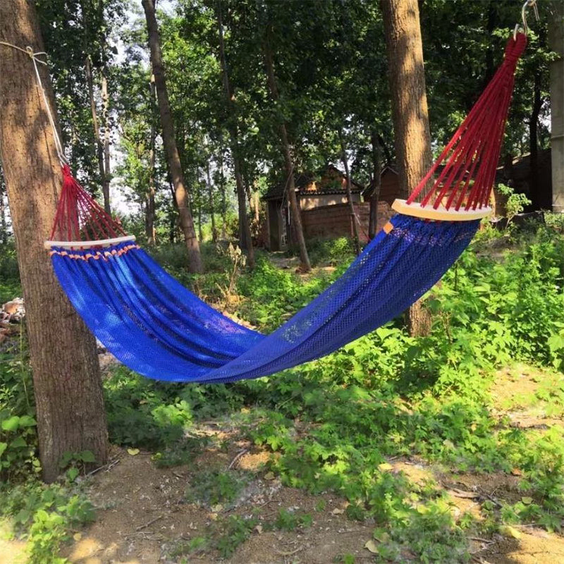 Arenzza upgraded camping hammock with ropes, shown hanging between trees in a scenic outdoor setting for sports and outdoors use.