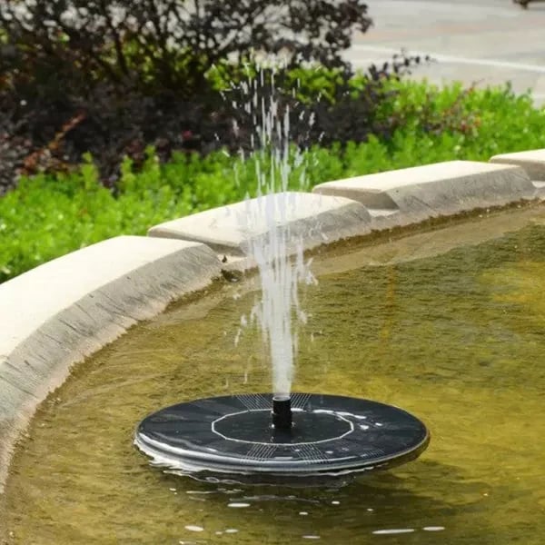 Arenzza solar powered fountain in a garden, showing water flowing from a garden tool-style fountain head in a lush outdoor setting.