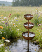 Arenzza Rain Catcher metal garden ornament used as plant support in a garden setting with rain droplets on it.