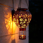 Aarenza solar-powered hot air balloon lantern in a garden setting, showcasing its colorful balloon design and solar panel base.