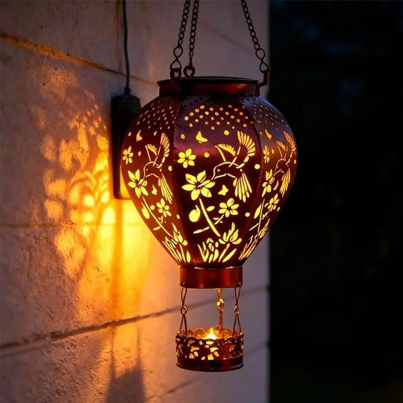 Aarenza solar-powered hot air balloon lantern in a garden setting, showcasing its colorful balloon design and solar panel base.