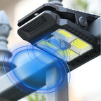 Arenzza outdoor solar clip light with motion sensor, mounted on a garden wall, illuminating the area during nighttime.