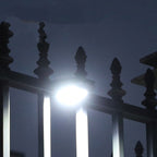 Arenzza outdoor solar clip light with motion sensor, mounted on a garden wall, illuminating a pathway at dusk.