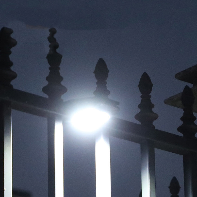 Arenzza outdoor solar clip light with motion sensor, mounted on a garden wall, illuminating a pathway at dusk.