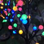 Arenzza solar-powered LED tree branch garden stake light illuminating a garden with a sleek black stake and bright LED bulbs